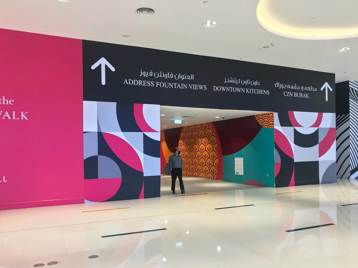 Un pasillo interior colorido presenta gráficos geométricos en las paredes y señales direccionales.