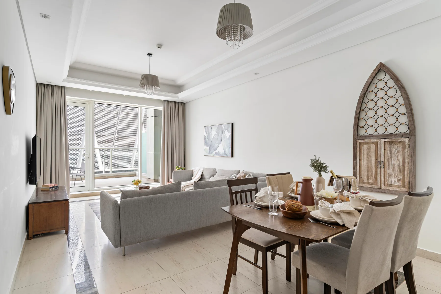 Una luminosa sala de estar y comedor con un sofá gris y una mesa puesta.