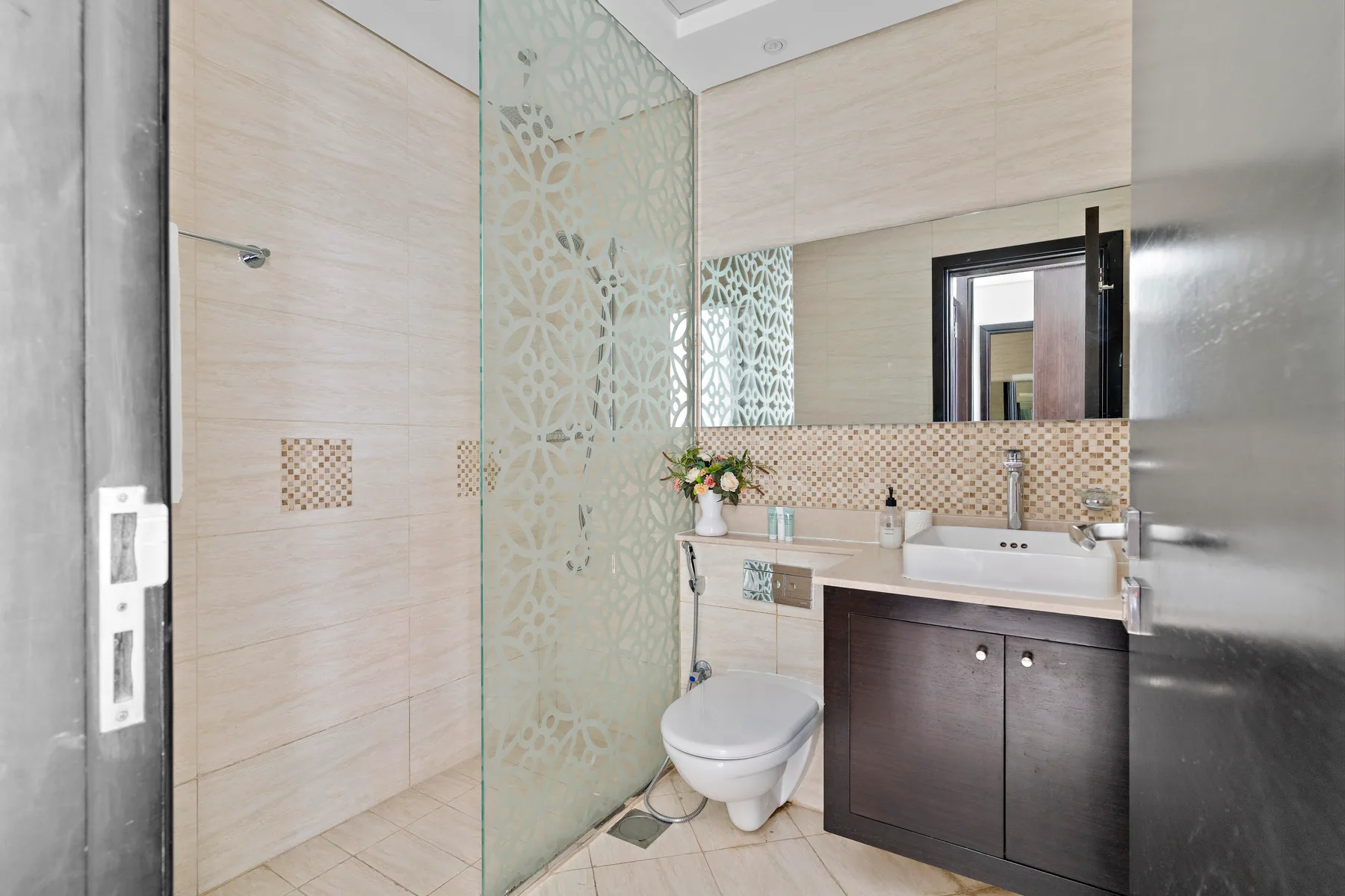 Un baño moderno con ducha de vidrio, inodoro y tocador oscuro.