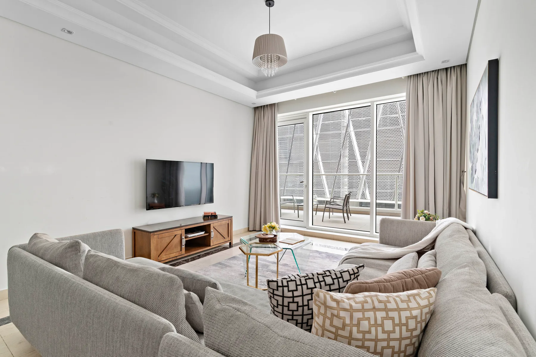 Una sala luminosa con asientos, un televisor y ventanas grandes.