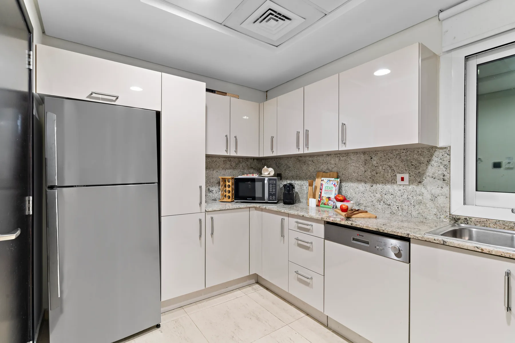 Una cocina moderna y luminosa con gabinetes blancos, un refrigerador y una encimera.