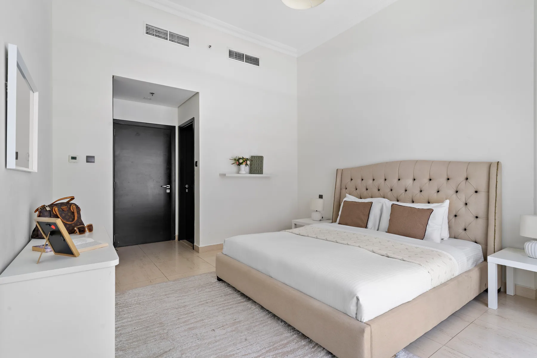 Un dormitorio luminoso con una cama grande y una puerta oscura.