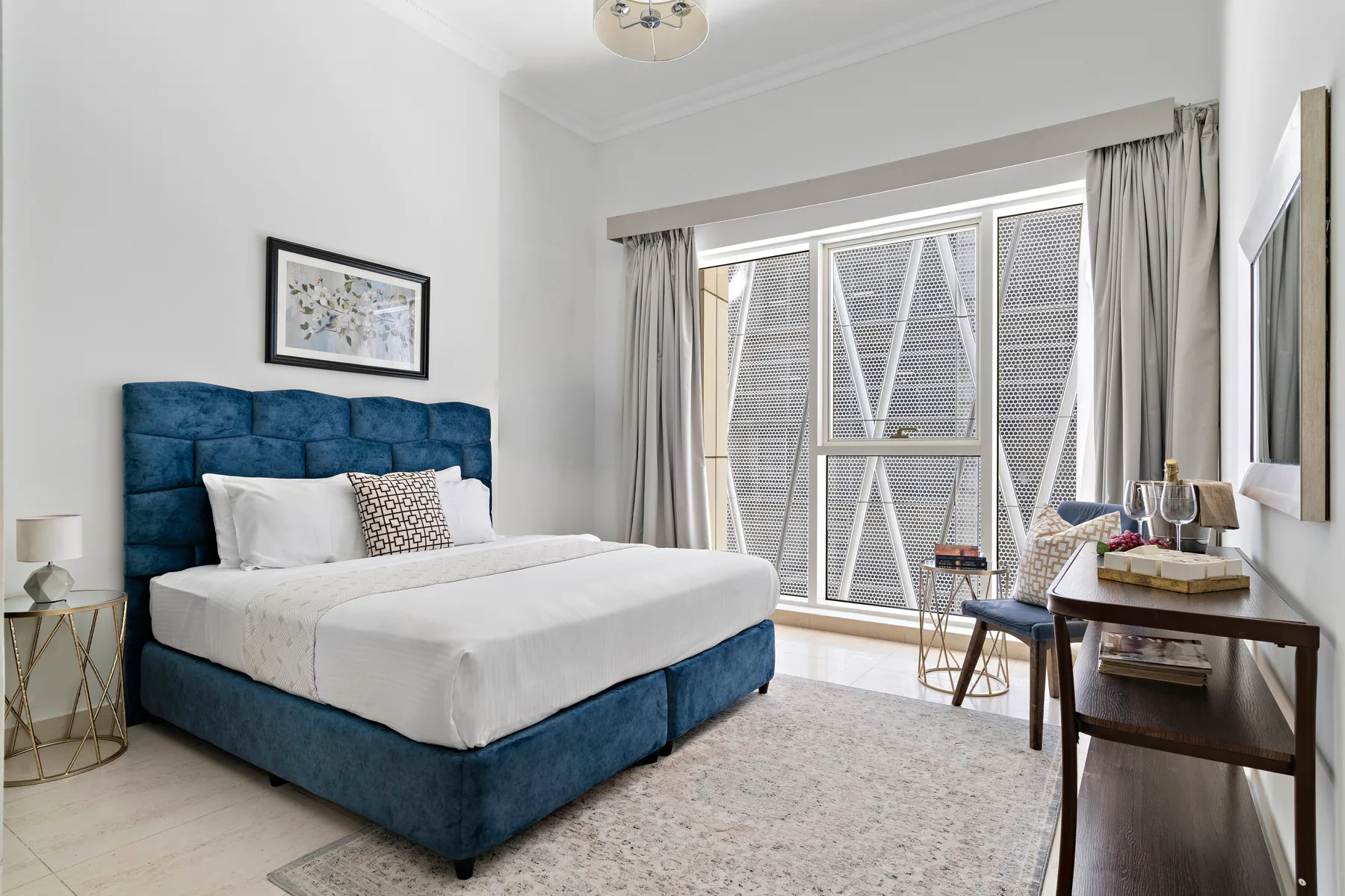 Un dormitorio con una cama junto a grandes ventanas y una zona para sentarse.