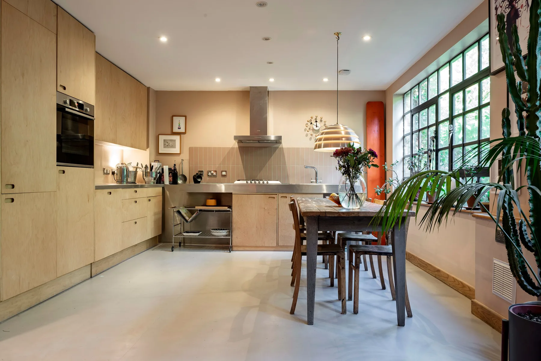 Una cocina abierta y comedor con una mesa larga junto a grandes ventanas.