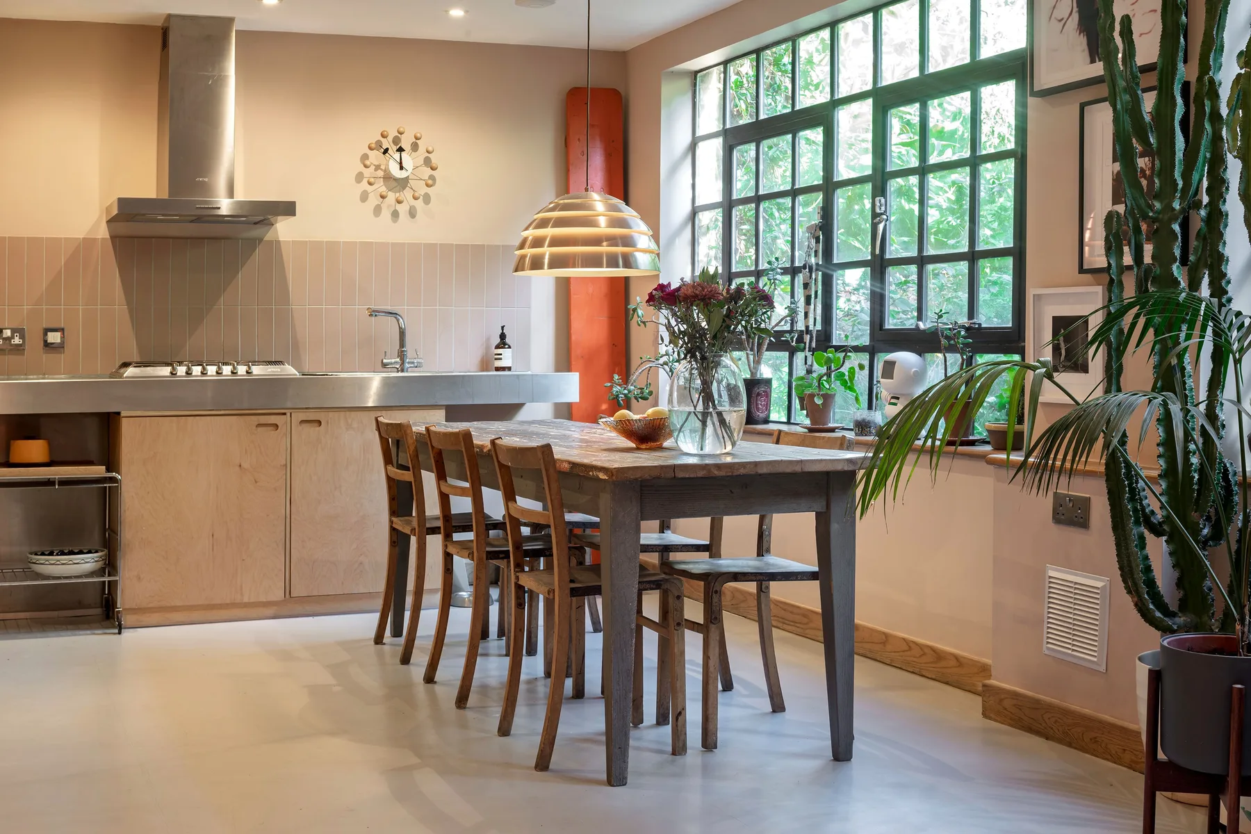 Una cocina y comedor con una larga mesa de madera junto a grandes ventanas.