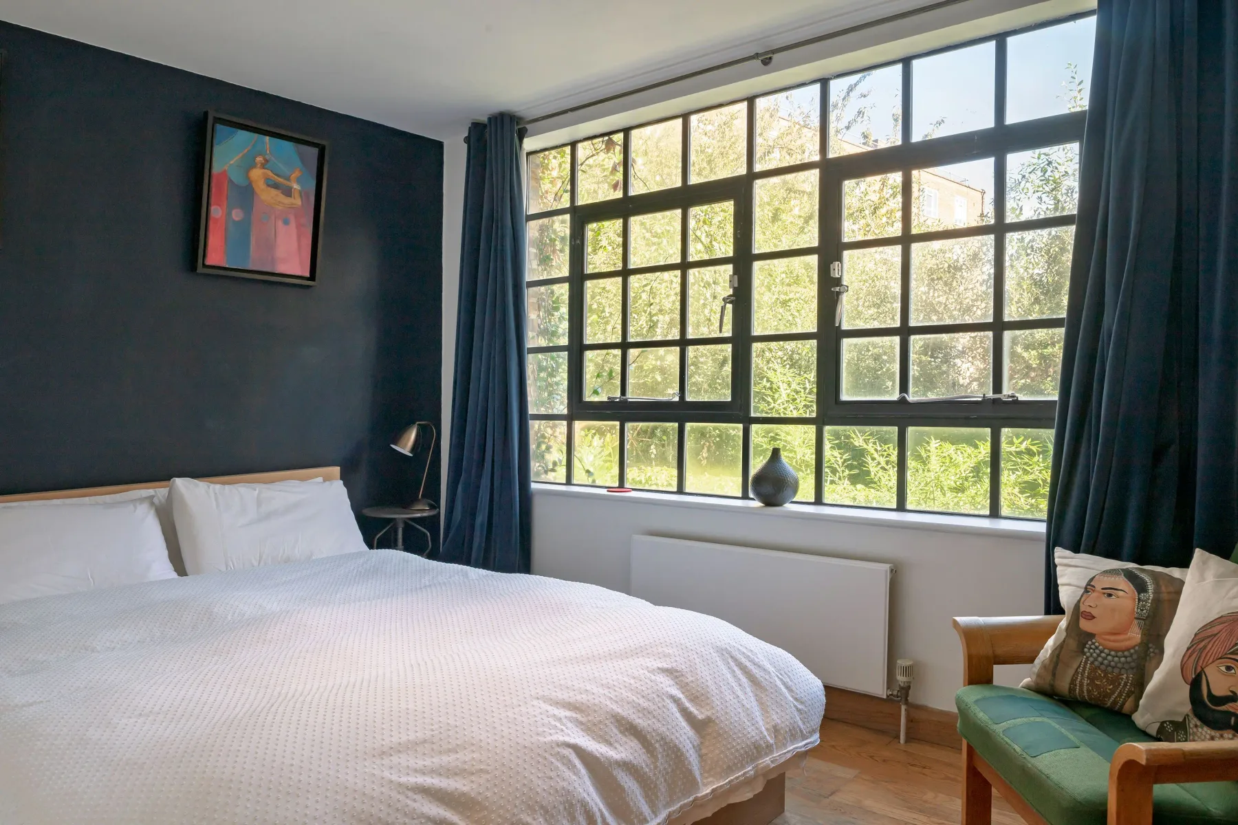 Un dormitorio con una gran ventana de cuadrícula y una cama.