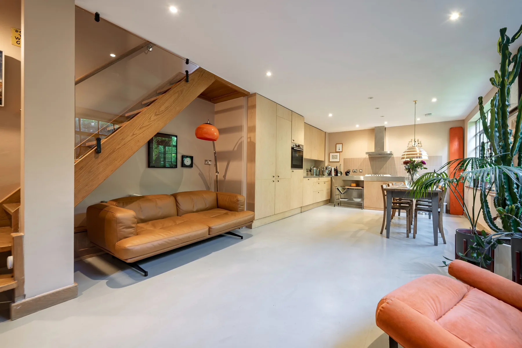 Una sala de estar y comedor de planta abierta, con un sofá bajo una escalera de madera.
