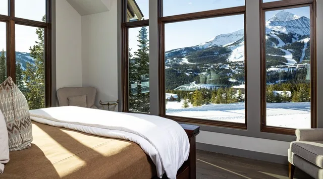 Un dormitorio con grandes ventanas que dan a un paisaje montañoso nevado.
