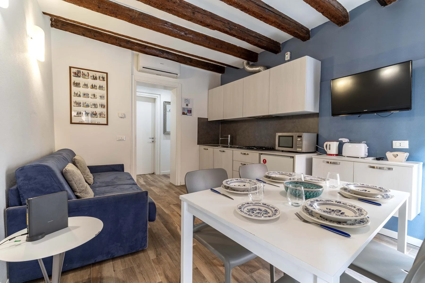 A combined living and dining area has a blue sofa beside a set dining table.
