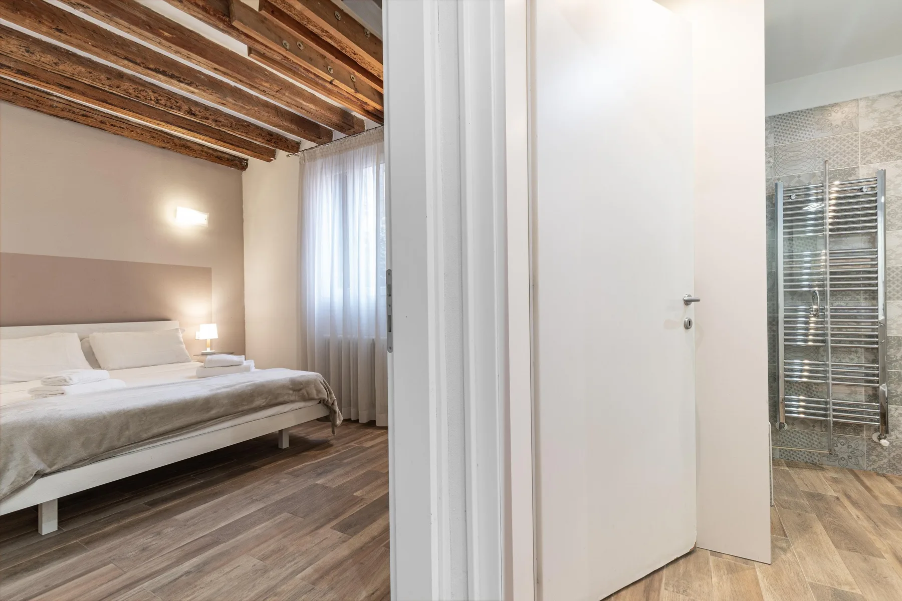 A bedroom with a bed and a view into an adjoining bathroom.
