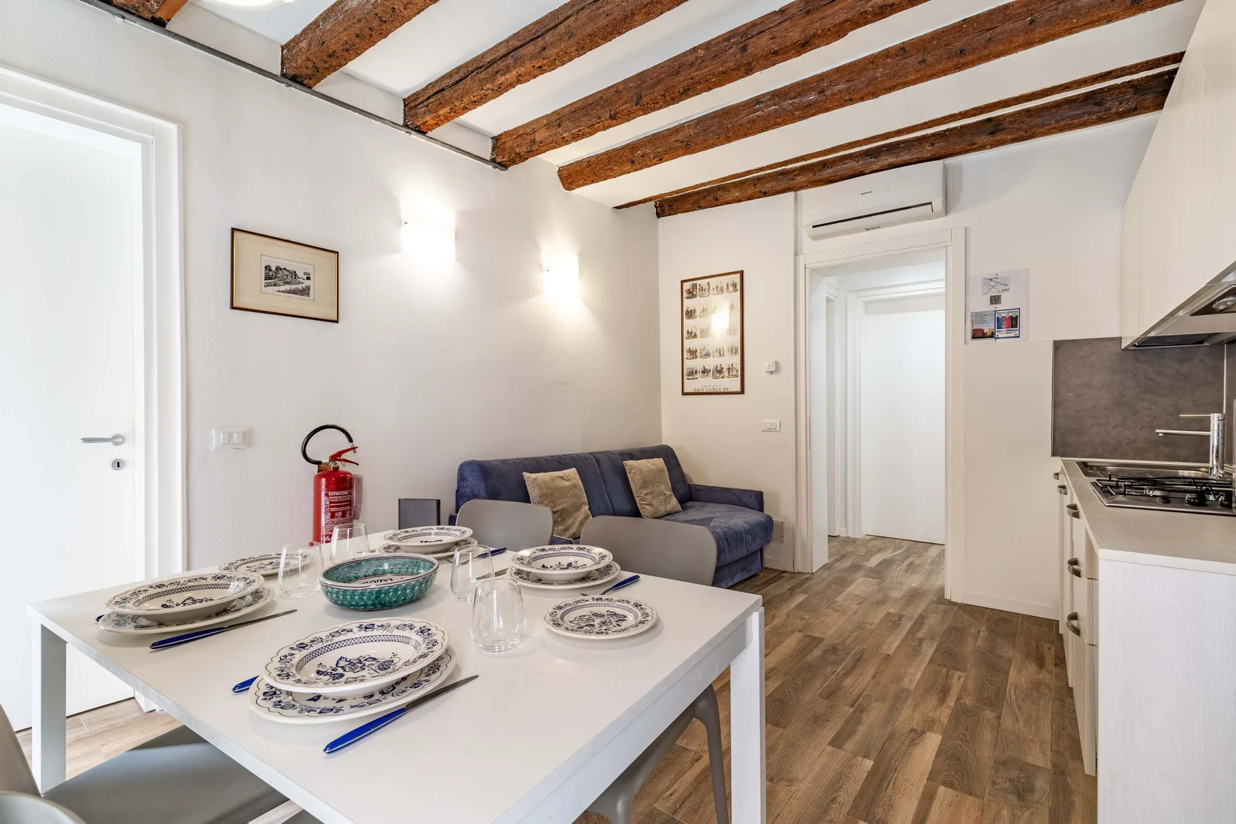 A dining area with a set table, seating, and exposed wooden ceiling beams.