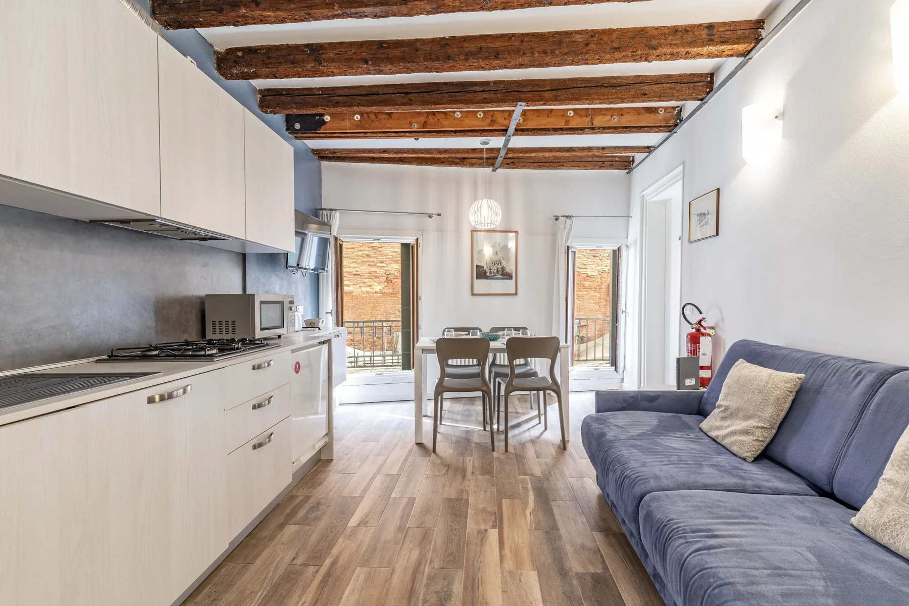 A bright open-plan living room with a kitchen, dining table, and seating.