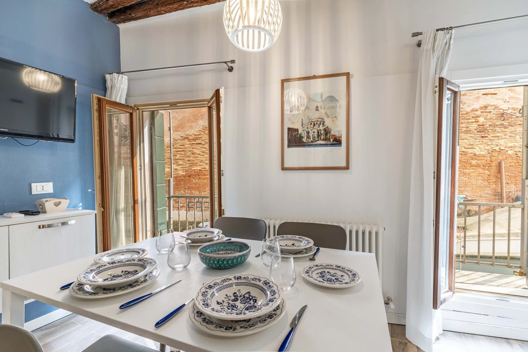 A dining area with a set table beside open doors to a balcony.