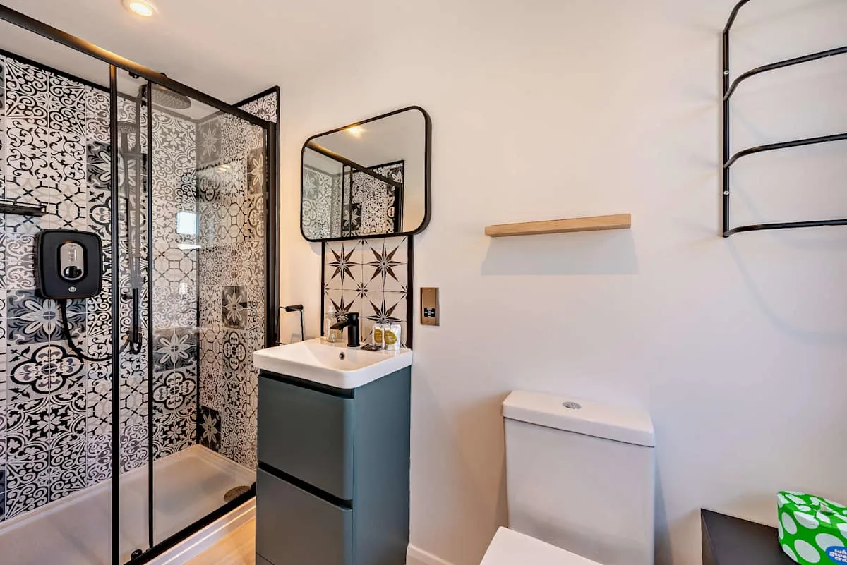 A bathroom with a patterned shower area, sink, and toilet.