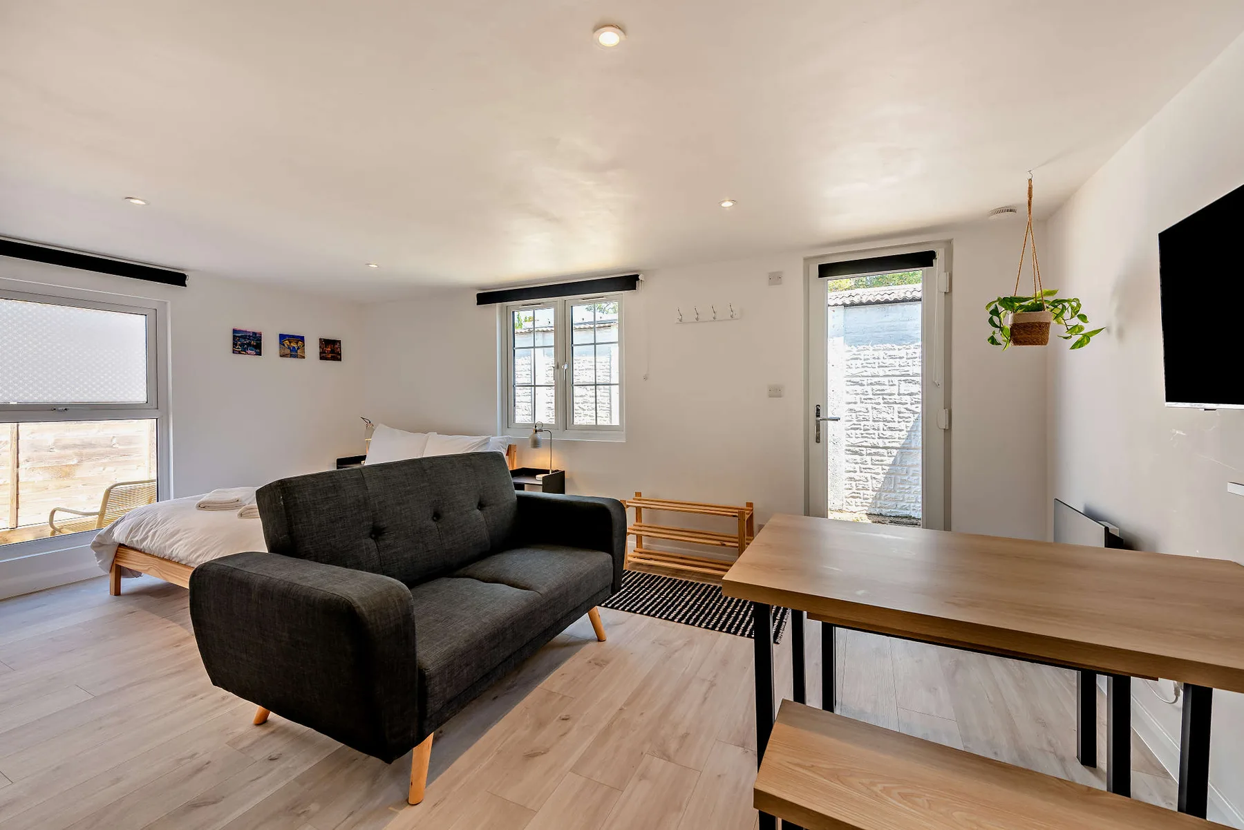 A bright living room with dark seating, a dining table, and windows.