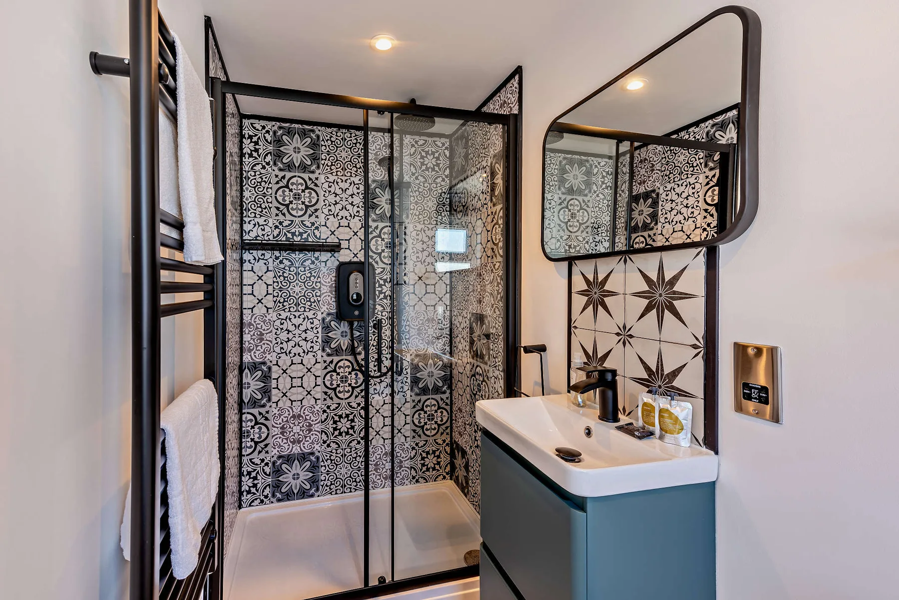 A bathroom with patterned wall tiles, a shower, and a sink.