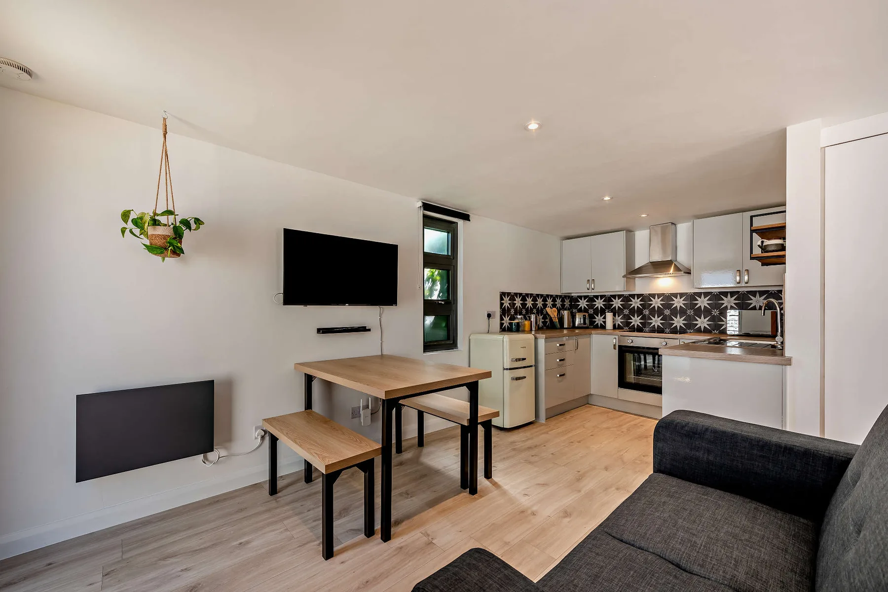 A combined living and kitchen area with a dining table and dark seating.