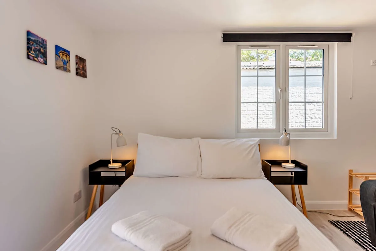 A bright bedroom with a bed beneath a window.