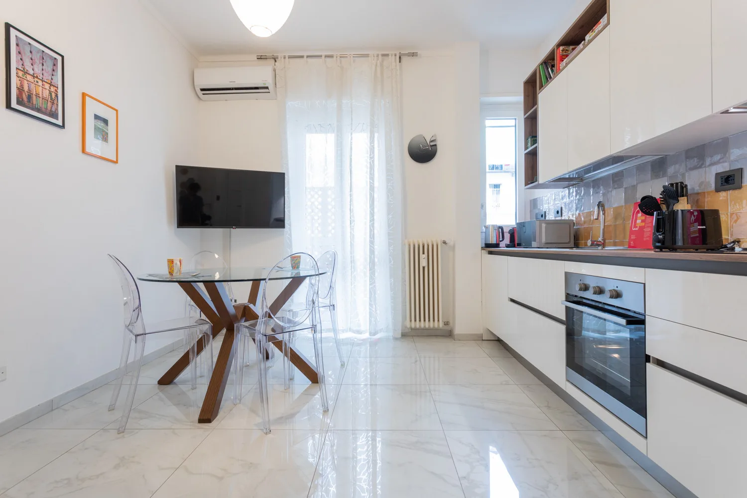 Una cocina y comedor luminosos, con una mesa de vidrio junto a la encimera.