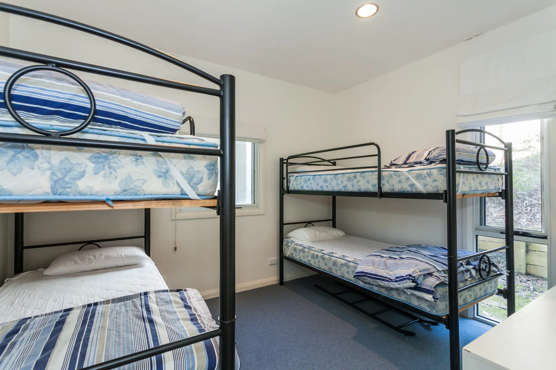 Un dormitorio con dos literas, ropa de cama estampada y ventanas.