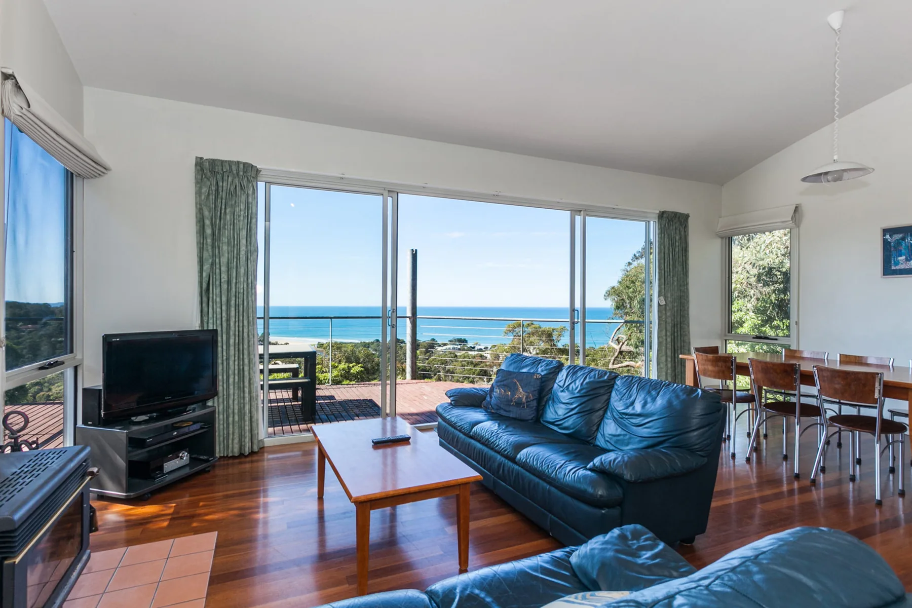 Sala de estar con asientos y grandes ventanales con vistas al mar.