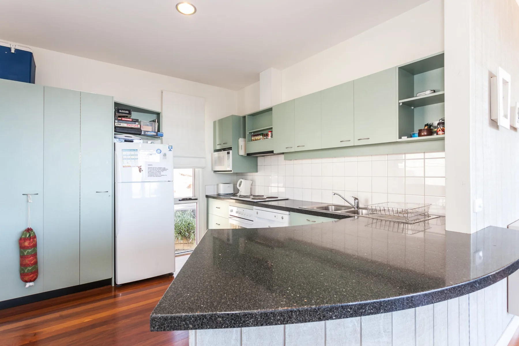 Una cocina luminosa con armarios claros y una encimera oscura.