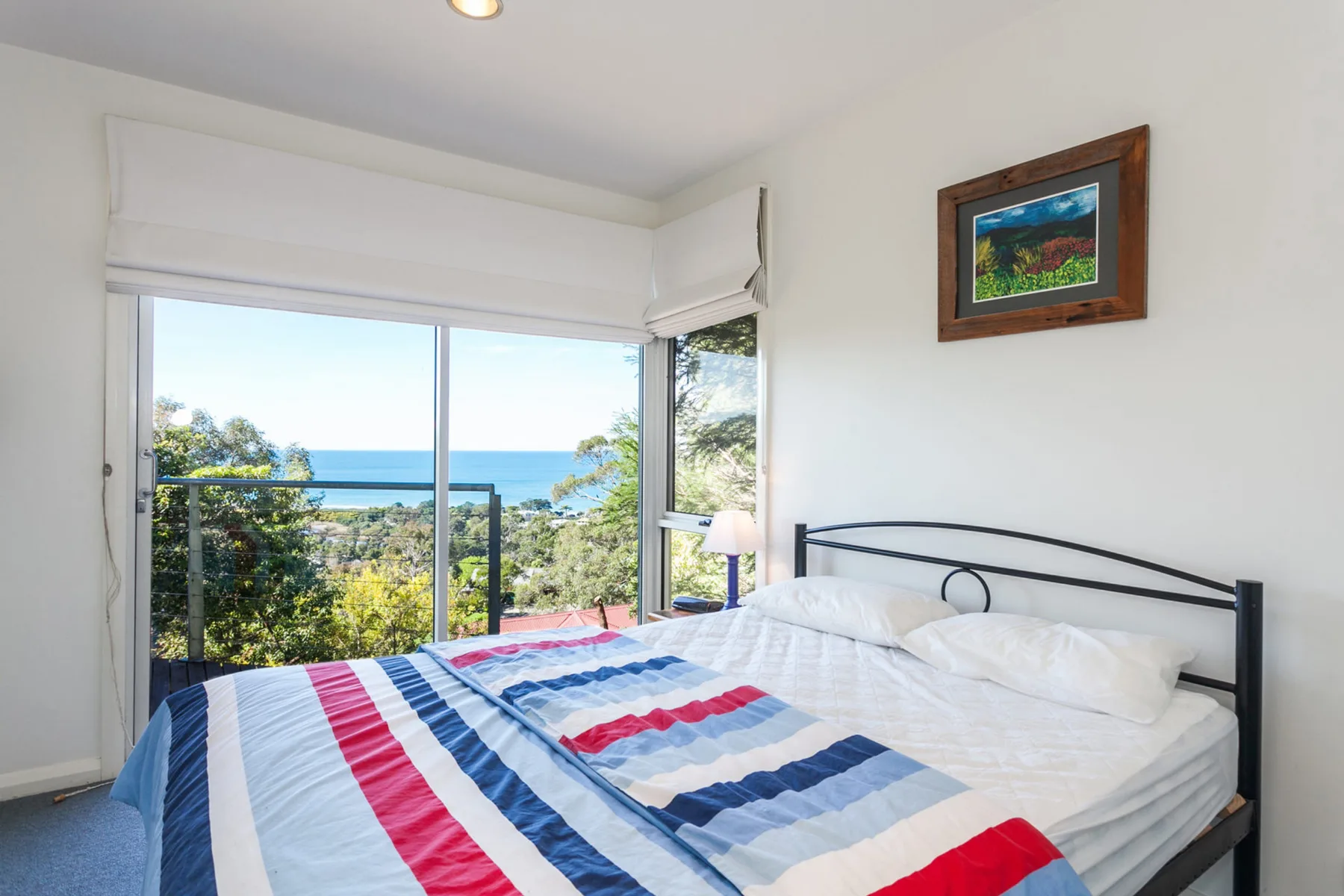 Un dormitorio con una cama junto a una gran ventana con vistas al mar.