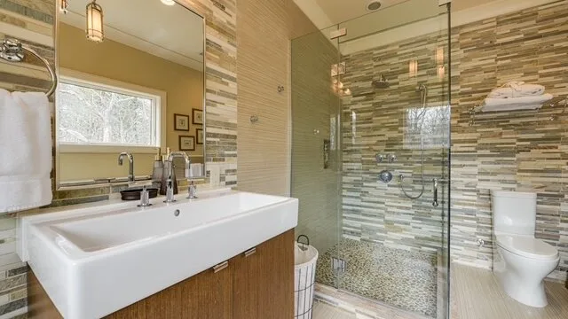 Un baño con lavabo, espejo y ducha con paneles de vidrio.