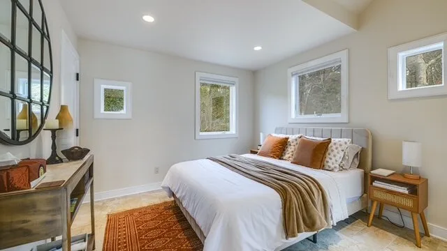 Un dormitorio luminoso con una cama tendida y varias ventanas.