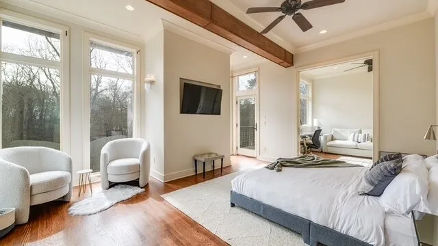 Un dormitorio luminoso con una cama grande, sillones y ventanas altas.