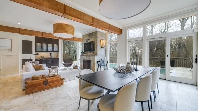 Una sala de estar y comedor de concepto abierto, con grandes ventanales y una mesa.