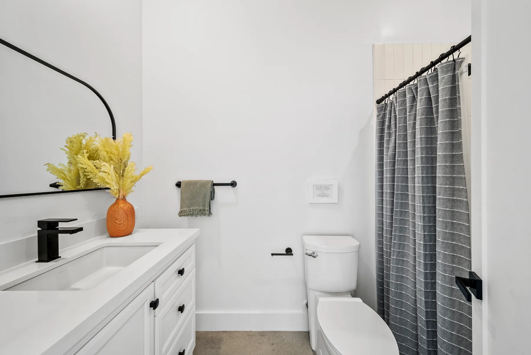 A bright bathroom with a vanity, toilet, and gray shower curtain.