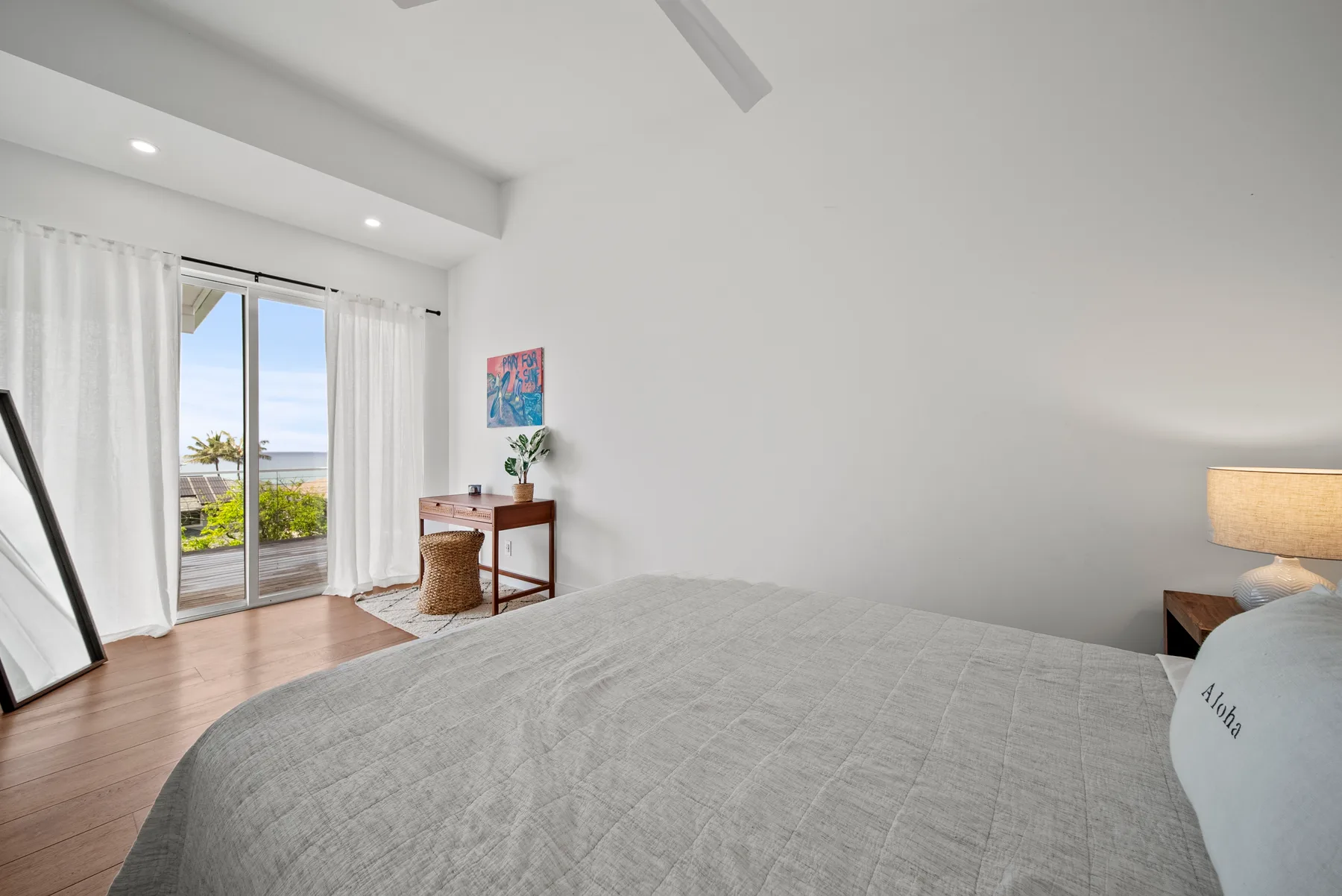 Bedroom with a bed, a desk, and sliding glass doors opening to a balcony.