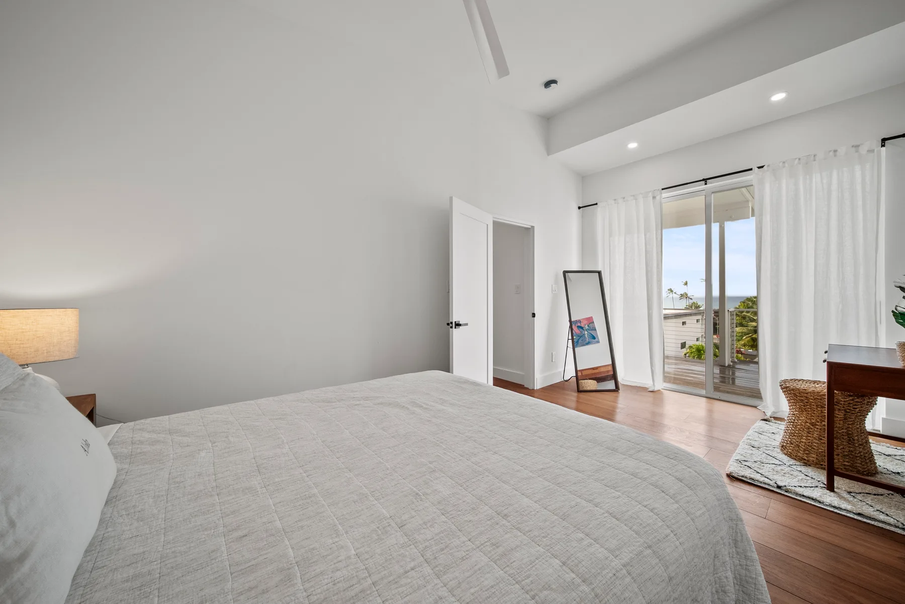 A bright bedroom with a bed facing glass doors and a balcony.