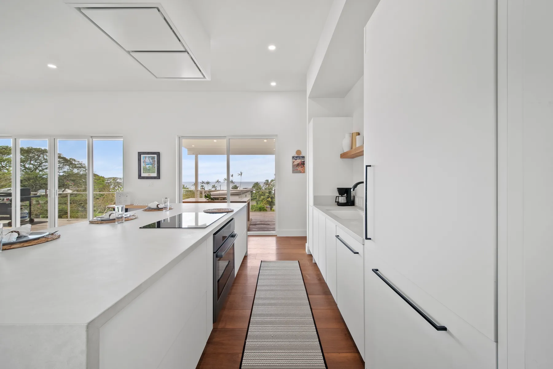 A bright modern kitchen with a long island and large windows.