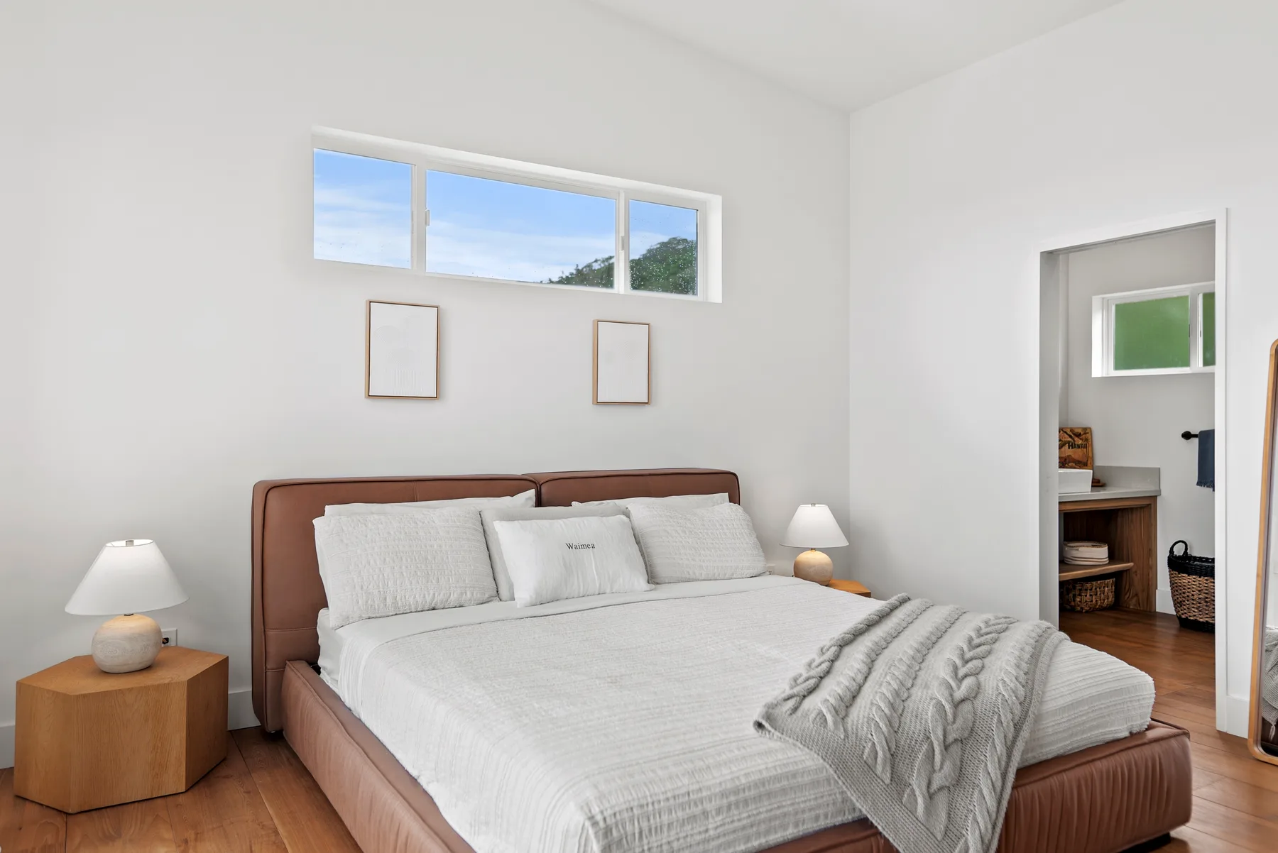 A bright bedroom with a neatly made bed and high windows.