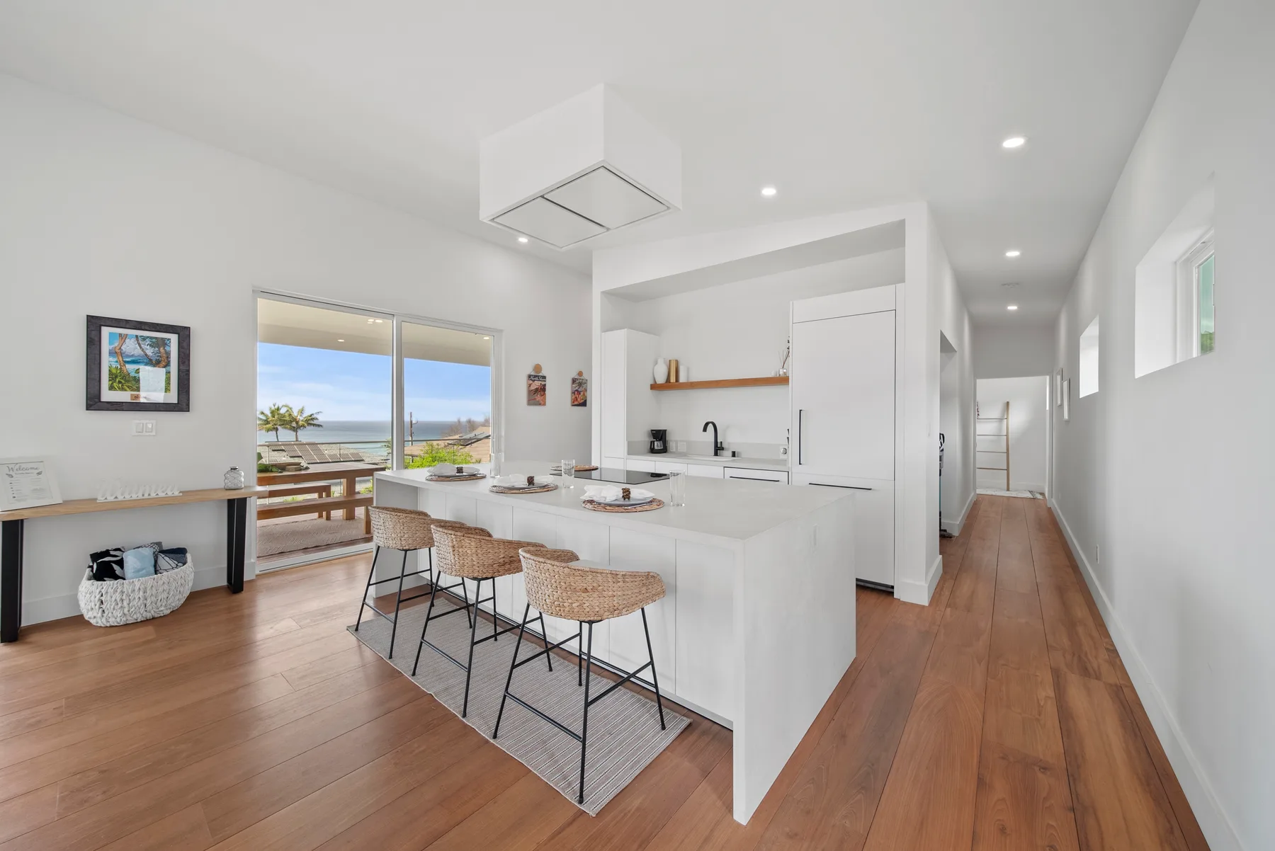 Una luminosa cocina abierta al comedor, con una isla blanca y grandes ventanas.