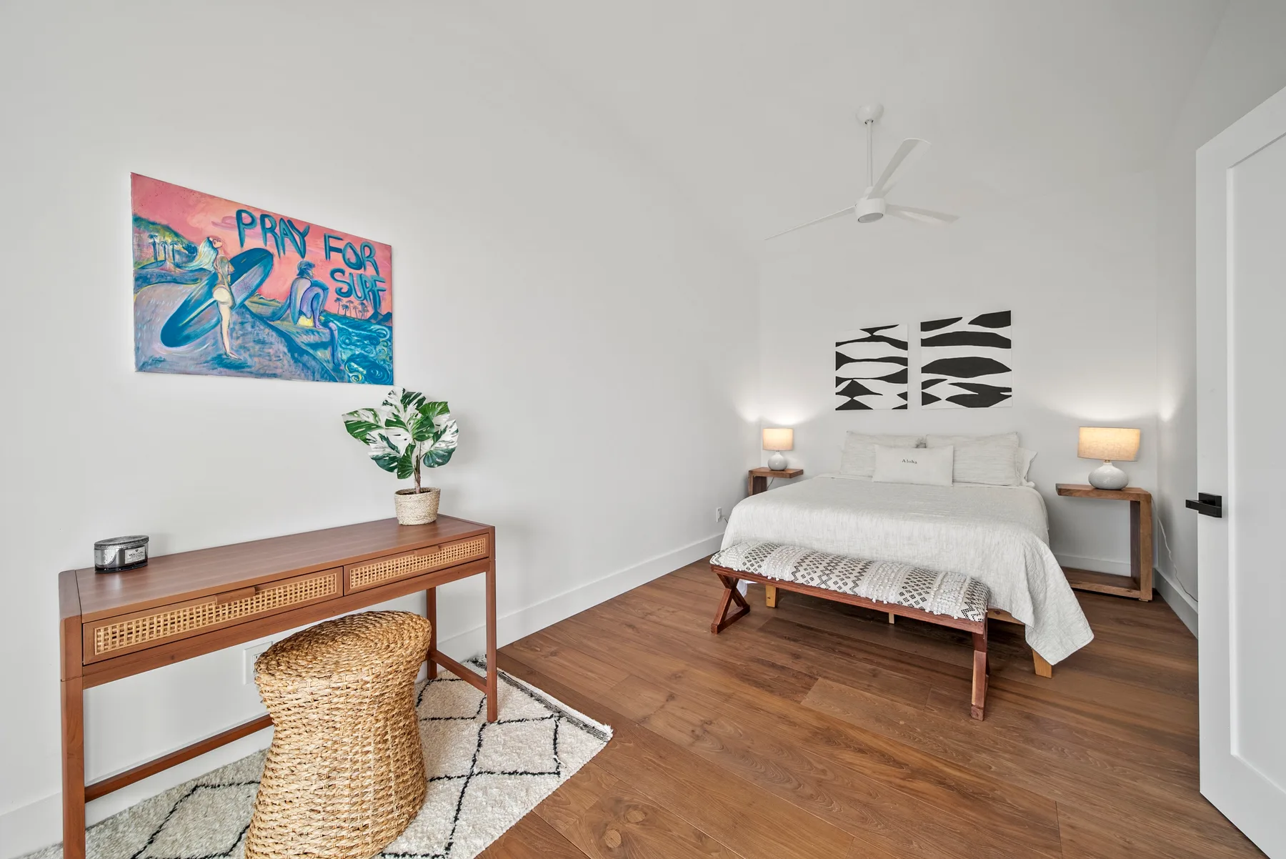 A bedroom with a bed, bedside tables, and colorful wall art.