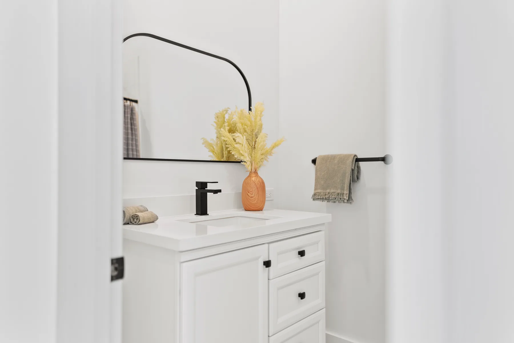 A bright bathroom vanity with a sink, mirror, and towel rail.