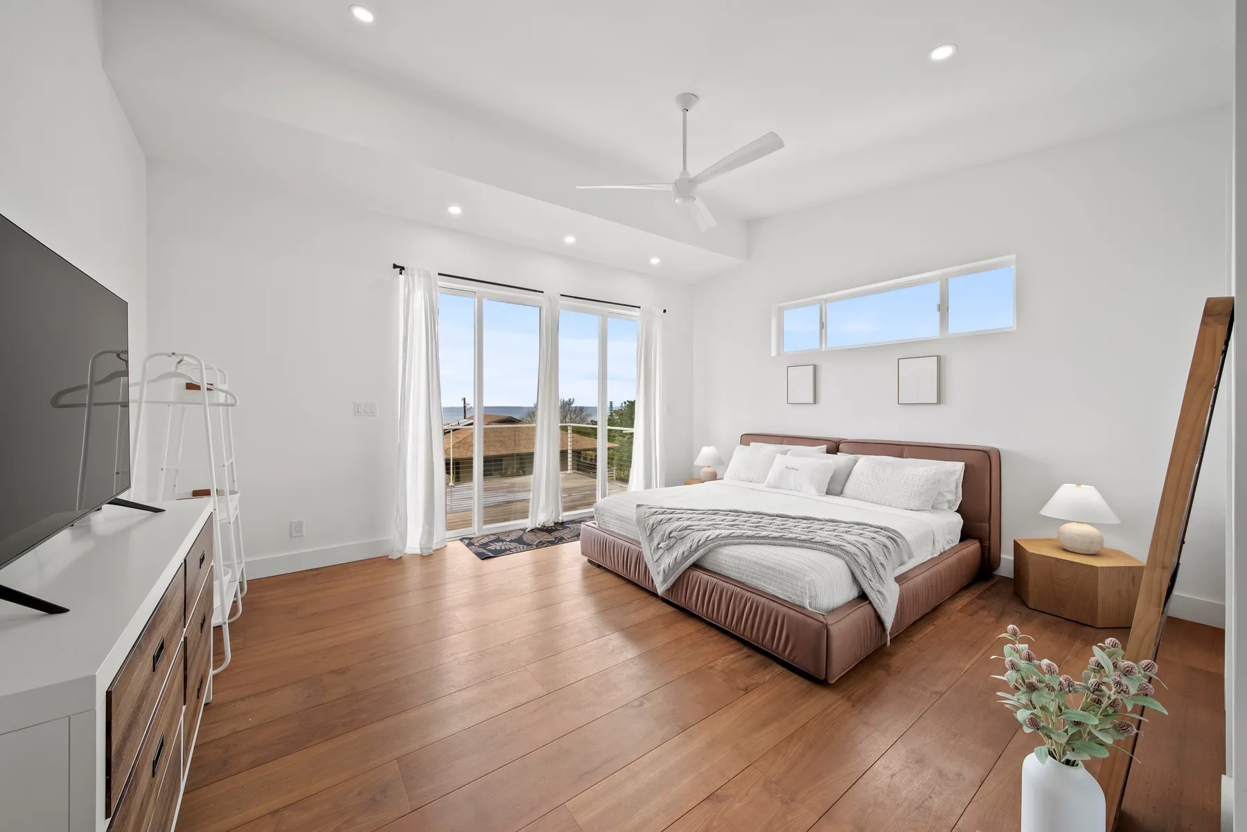 A bright bedroom with a bed and glass doors opening to a balcony.