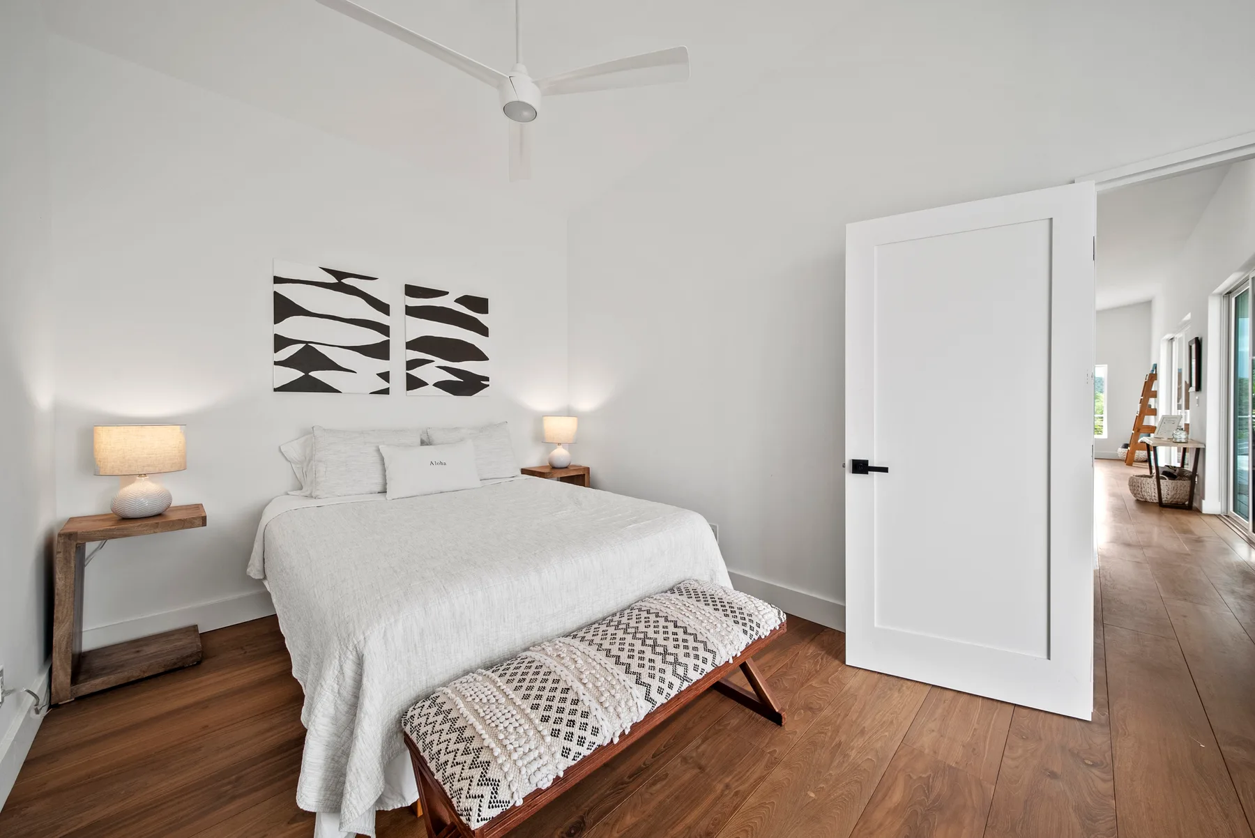 A bright bedroom features a neatly made bed and matching bedside lamps.