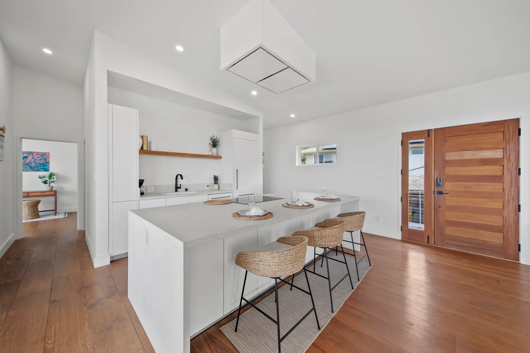 A bright kitchen with a large island and woven stools.