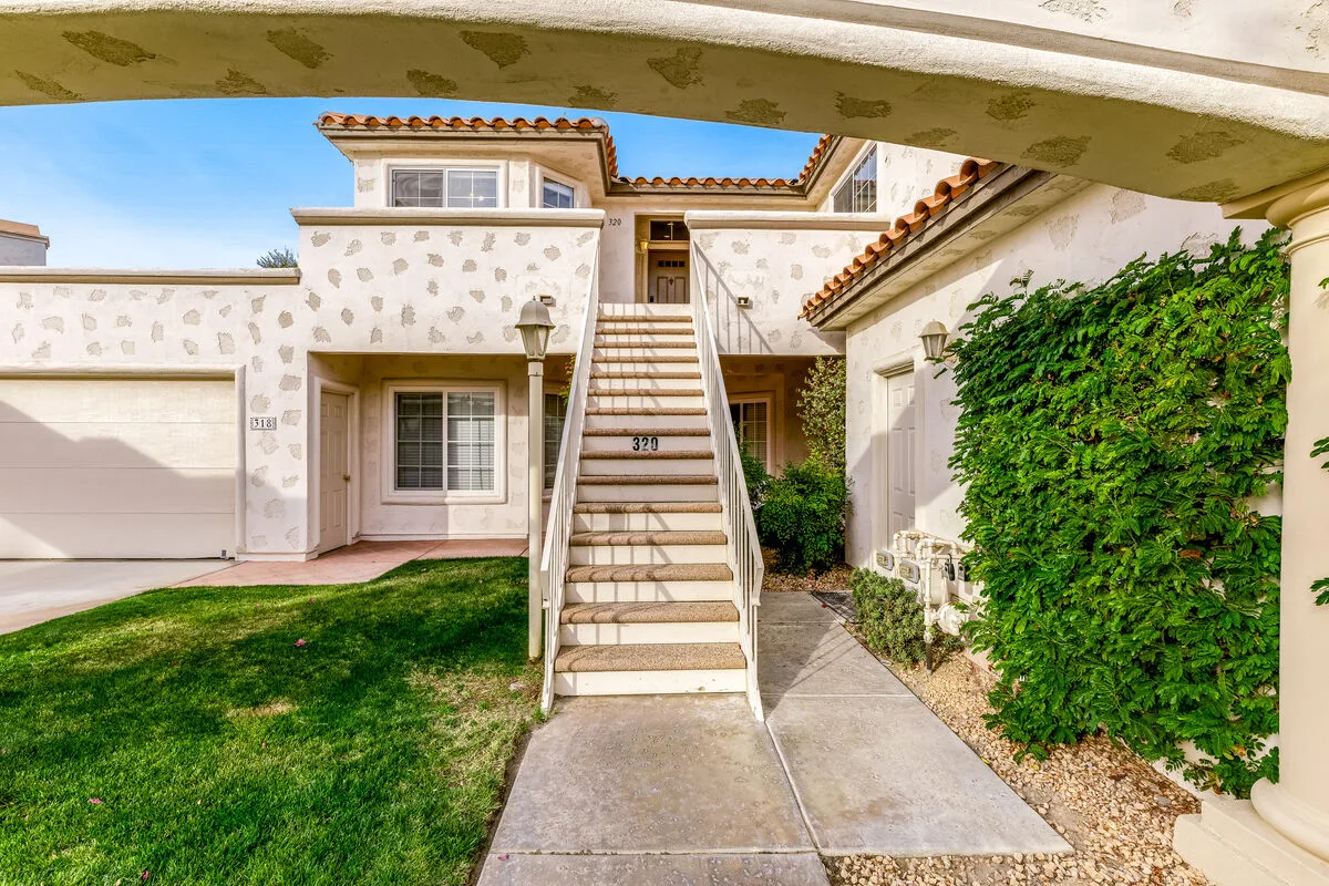 Exterior de una vivienda de estuco con una escalera exterior hacia una entrada superior.