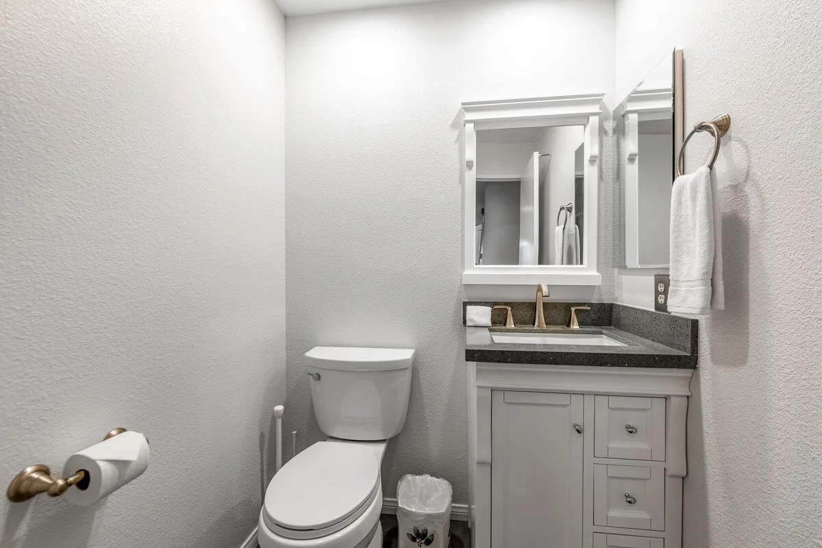 Un baño con inodoro, tocador y espejo en la pared.