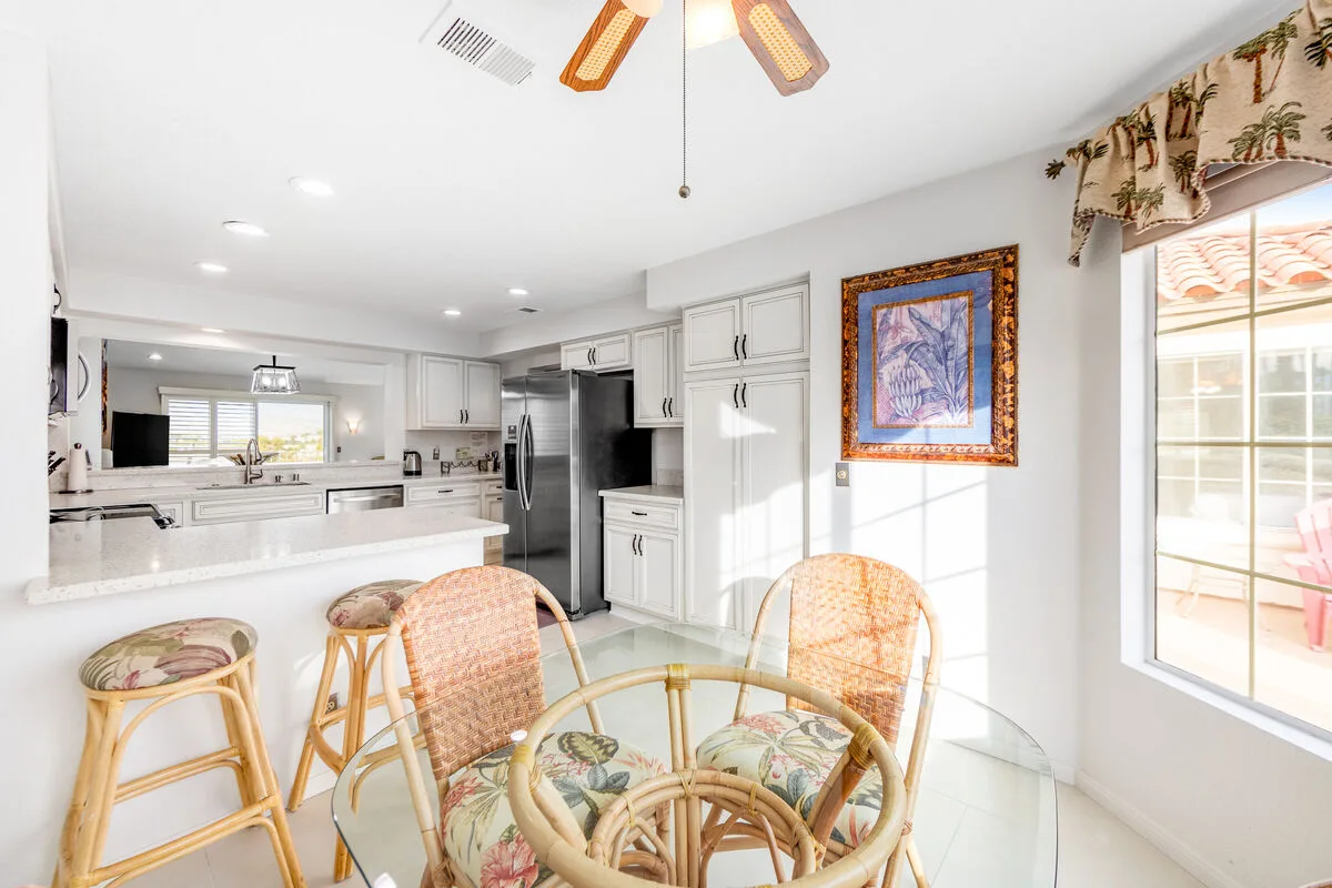 Una luminosa cocina con comedor, una barra y una mesa redonda de vidrio.