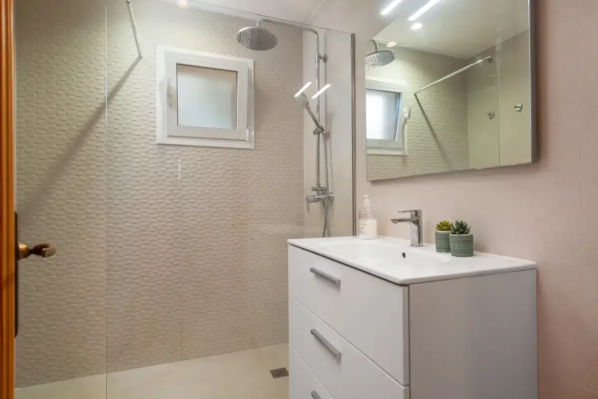 A bathroom with a vanity, mirror, and shower.