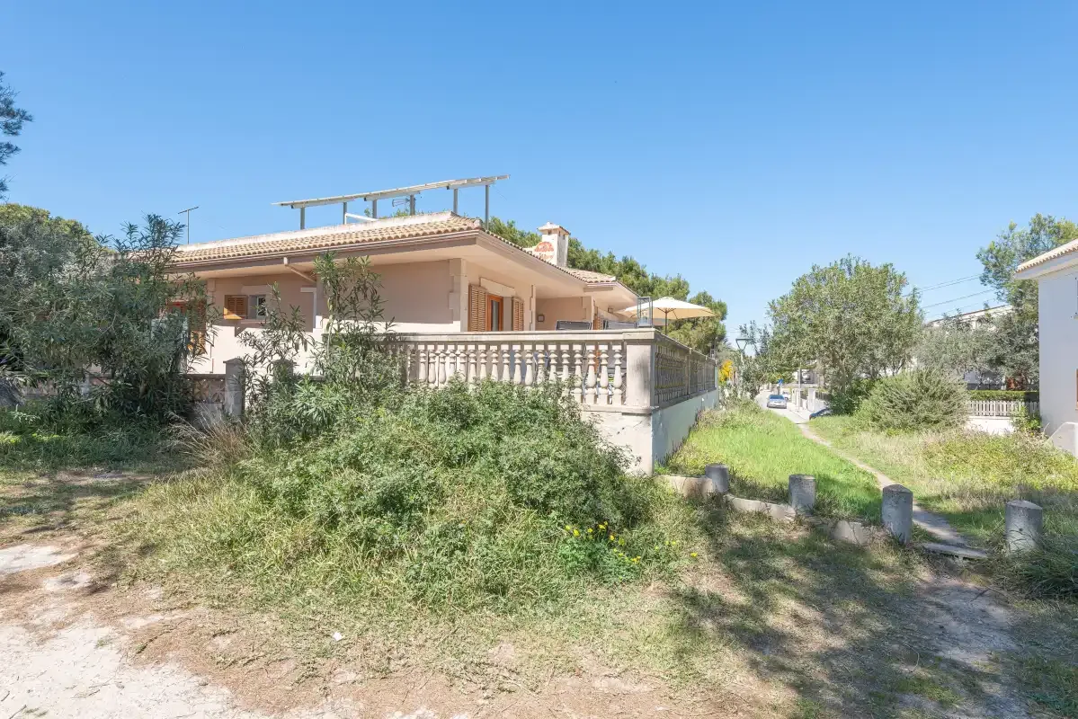 A low house with a terrace and garden under a clear sky.