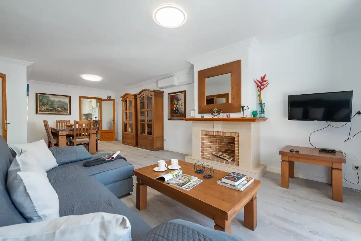 A living room with a sofa, wooden coffee table, fireplace, and wall-mounted television.