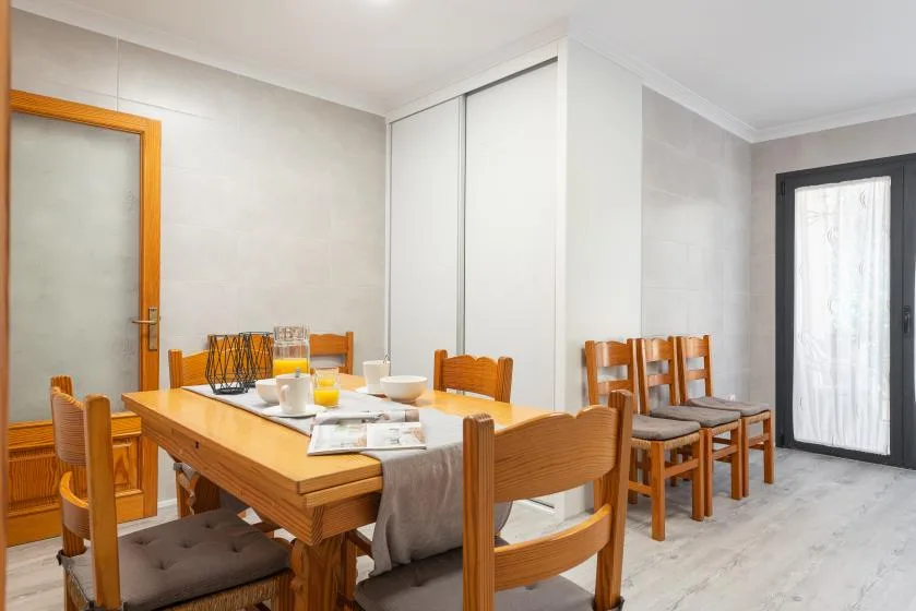 A dining area with a wooden table and chairs beside a glass door.
