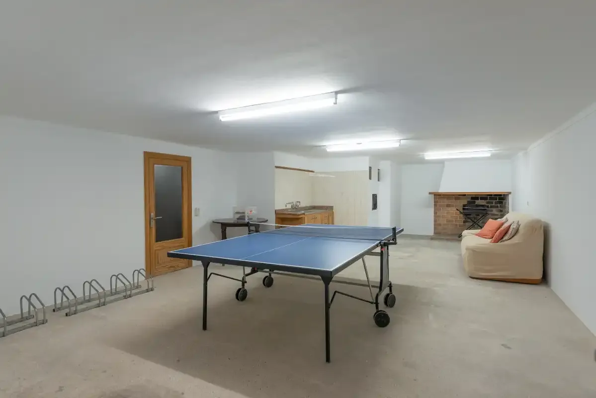 A basement recreation room with a ping-pong table and seating.